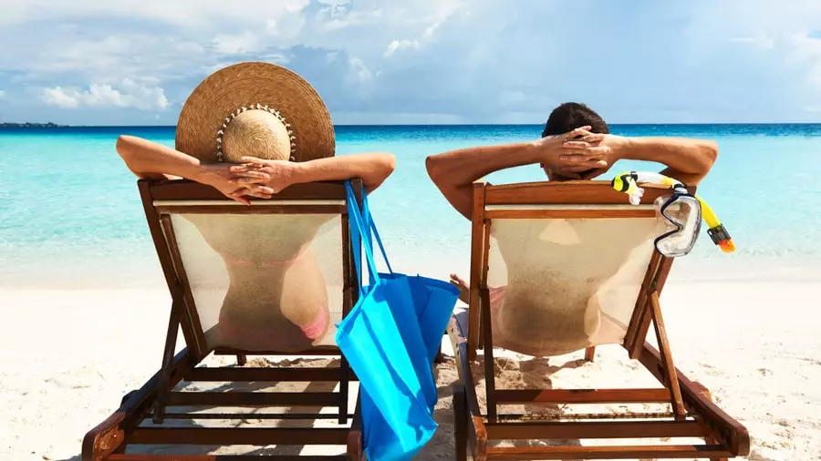 Two people laying on sunbeds image.