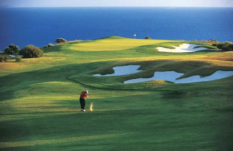 Man taking a swing shot over a golf course.